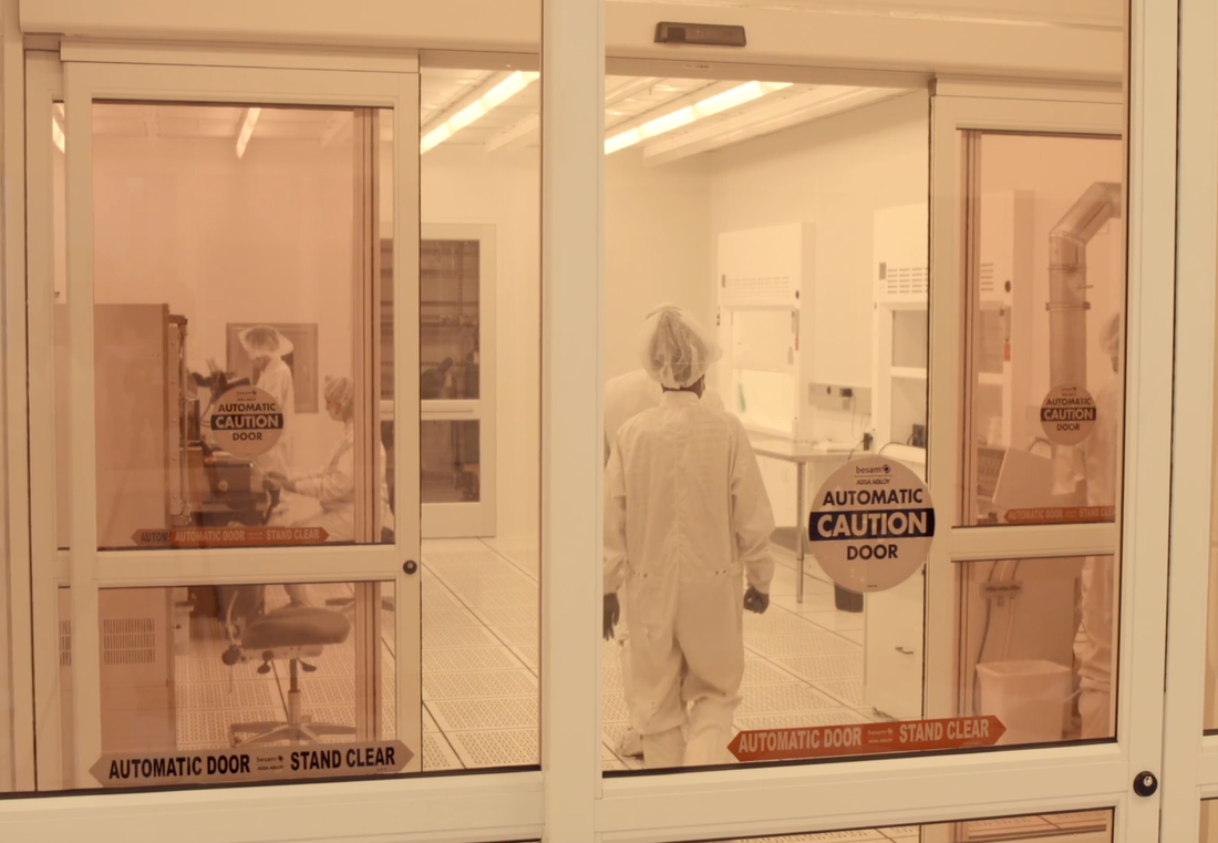 people in white containment style outfits in a white lab area